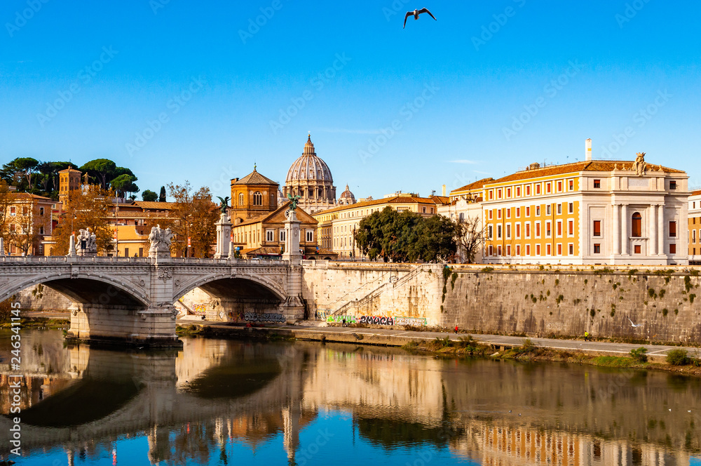 Tiber river streams, Ponte Vittorio Emanuele II bridge, flying seagulls and Rome cityscape view with St. Peter dome on the background