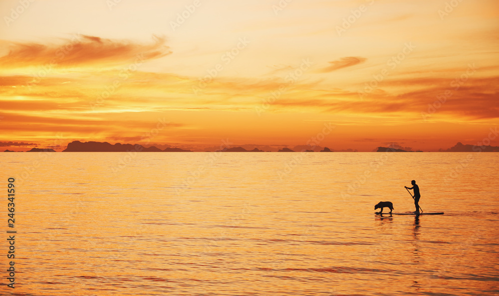 Man with dog on a sea in the sunrise. Thailand, Phangan
