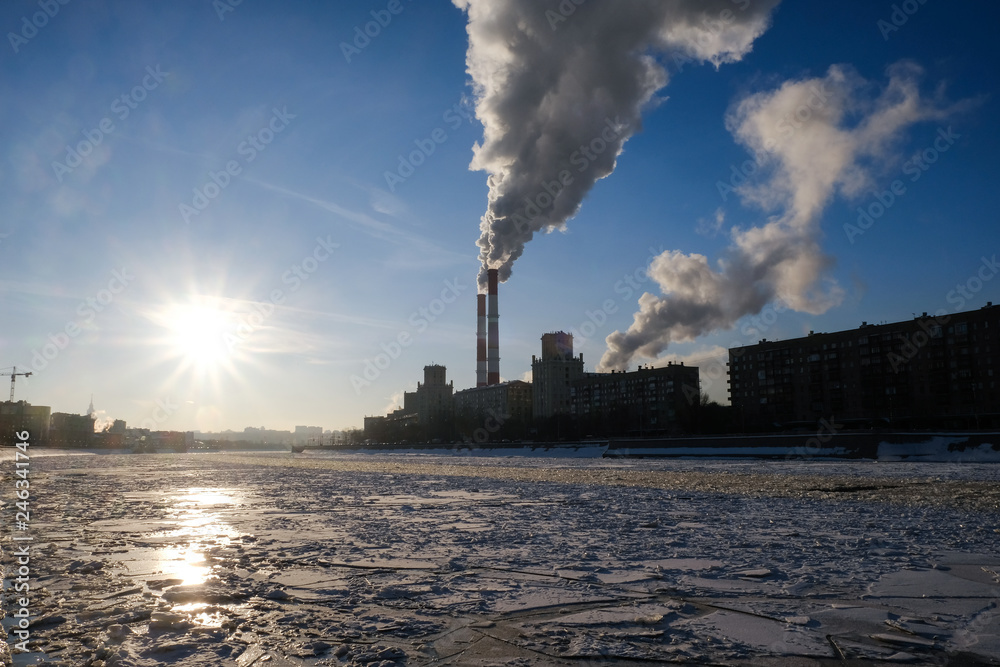 Smoke from heating system chimney close to the frozen Moscva river in Moscow during winter