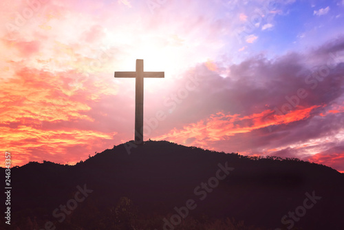  Concept of Jesus Christ: white cross on sunset sky background