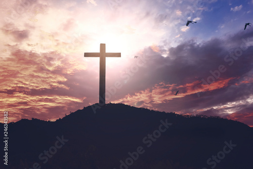  Concept of Jesus Christ: white cross on sunset sky background