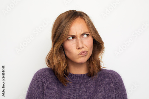 portrait of a young woman skeptical and thinking on white background