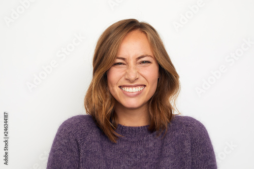 portrait of a young happy woman smiling giggles on white background looking in camera © Martin Villadsen