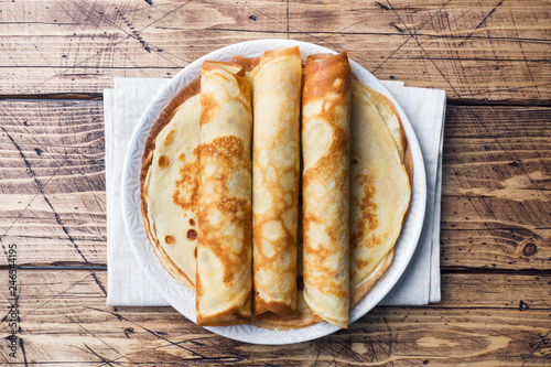 Thin pancakes on a plate. Wooden background. Close up.