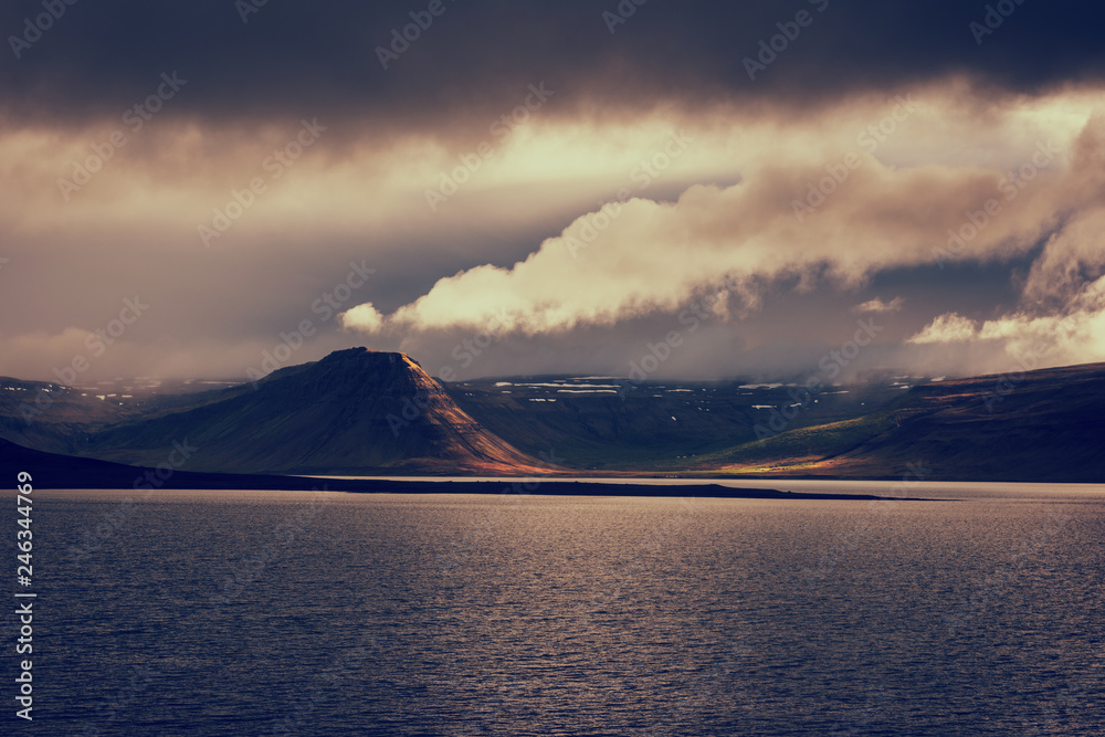 Amazing nature, night scenic landscape in moonlight with water, volcanic mountains and cloudy sky, Iceland. Travel outdoor summer background