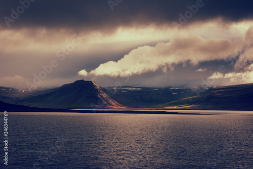 Amazing nature, night scenic landscape in moonlight with water, volcanic mountains and cloudy sky, Iceland. Travel outdoor summer background