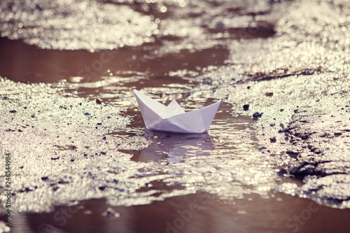 The paper boat floats through the spring puddles. Children's entertainment.