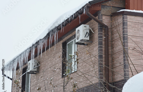 House rooftop, rain guuter in ice and icicles in cold snow winter.