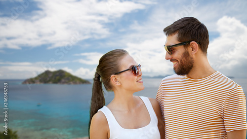 travel  tourism and people concept - happy couple in sunglasses outdoors over tropical beach on seychelles island background