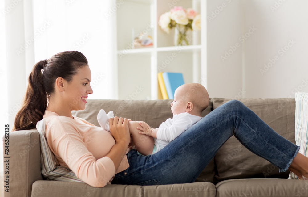 family, motherhood and people concept - happy mother with little baby boy lying on sofa at home