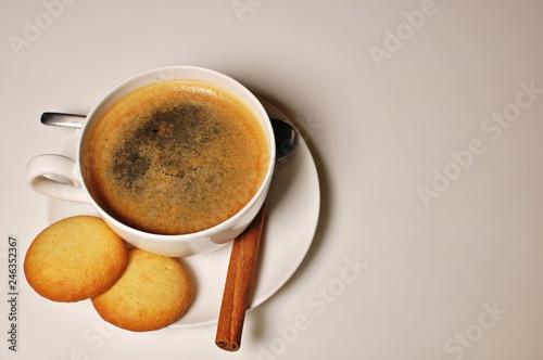 Hot cup of cappuccino with biscuits and cinnamon stick as decoration. Top table  copy text