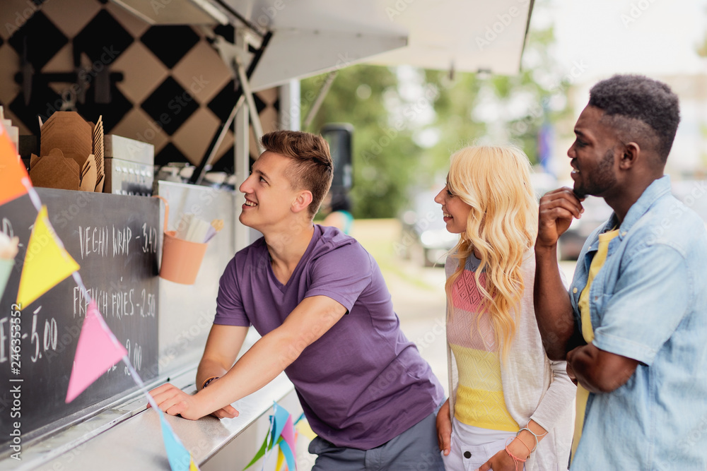 Φωτογραφία street sale and people concept - happy customers queue or friends at food truck