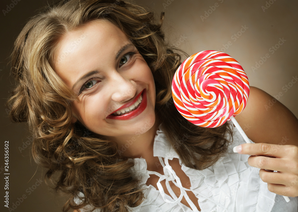 Lollipop in hand. Beautiful curly girl with  candy.