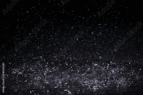 Raindrops are breaking on the surface on a black background.