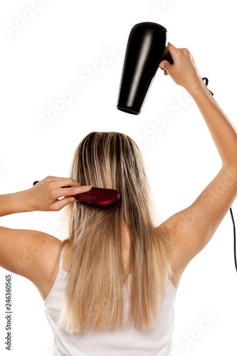 unknown young woman drying her hair with hair dryer on white backgrund