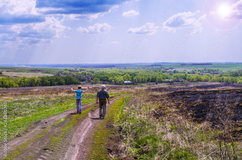 Obraz premium A boy and a man walking on a dirt road on a summer day in the far sides of the village, instagram.
