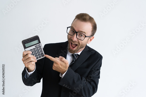 Excited accountant showing calculator. Optimistic young businessman in glasses looking at camera and screaming. Finance concept