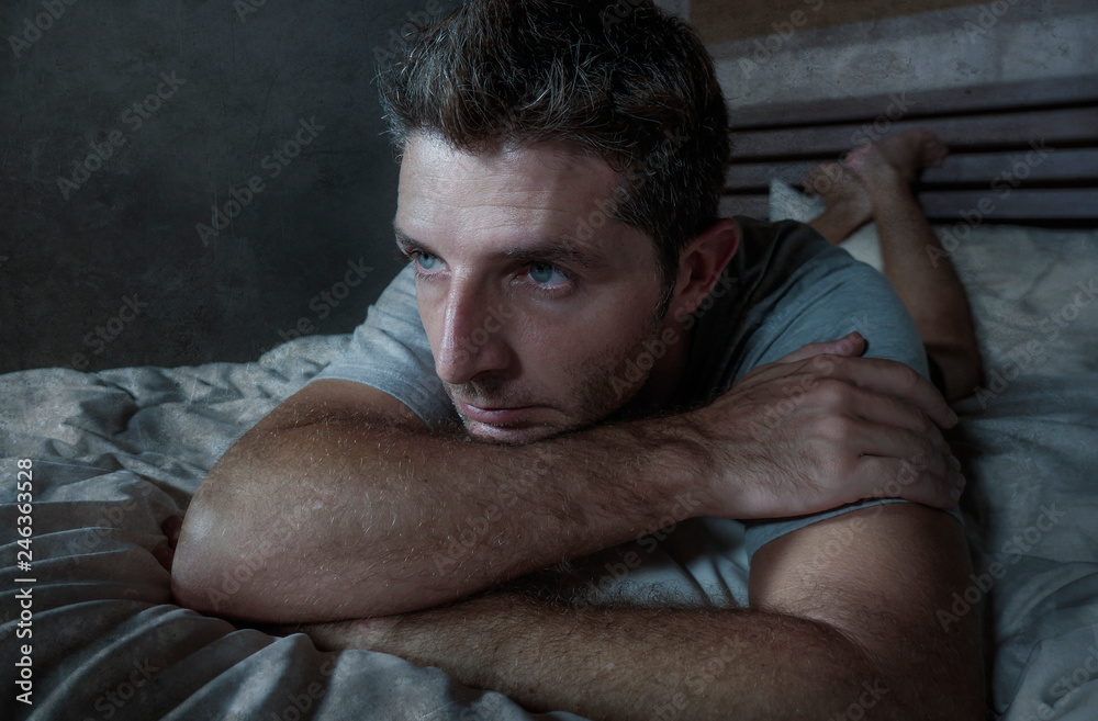 young sad and depressed sleepless man lying on bed worried and thoughtful at home bedroom suffering depression problem feeling unwell and desperate broken heart young sad and depressed sleepless man lying on bed worried and thoughtful at home bedroom suffering depression problem feeling unwell and desperate broken heart