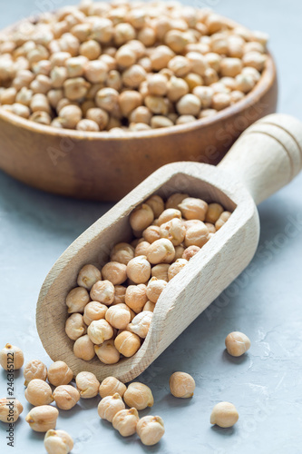 Dry chickpeas in wooden bowl and in the scoop, vertical