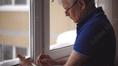 Working form home. Mid aged man with glasses use cellphone. Mature elderly man using smartphone.