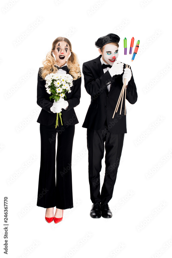 crazy clown looking at firecrackers near woman with flowers isolated on white