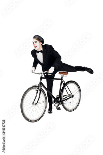 cheerful clown in suit riding bicycle isolated on white