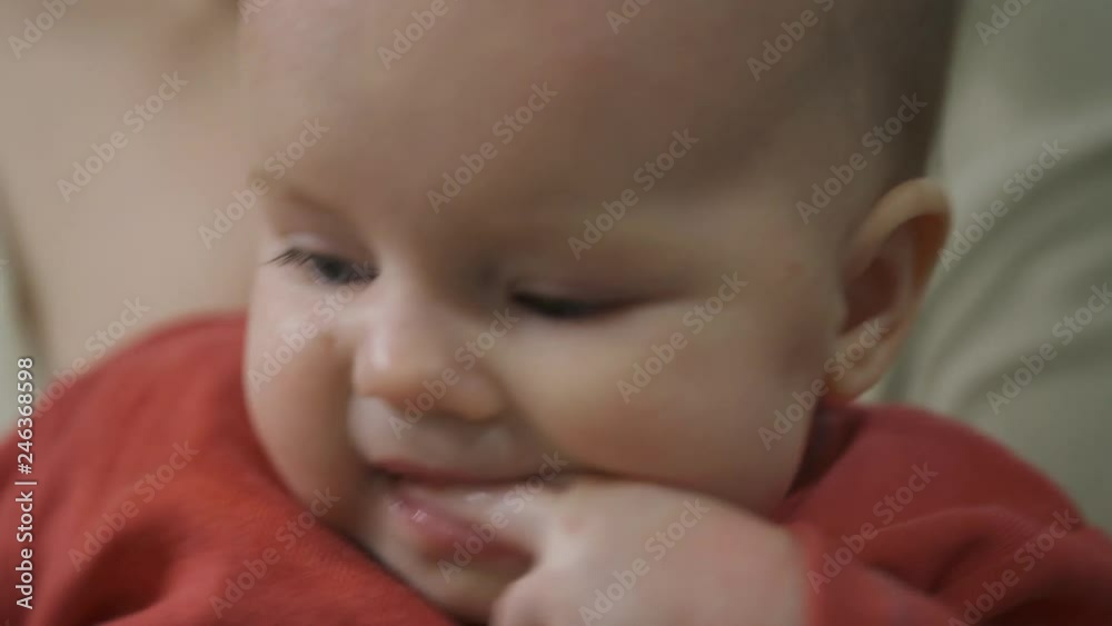A little one-year-old girl sucks her fingers. Her teeth are pierced. The child looks into the camera. A little one-year-old girl sucks her fingers. Her teeth are pierced. The child looks into the camera.