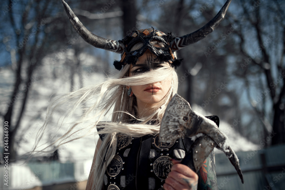 Portrait of beautiful warrior woman in image of viking with horned helmet and ax. Portrait of beautiful warrior woman in image of viking with horned helmet and ax.
