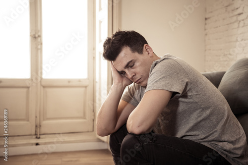 Young man suffering from depression lying on sofa alone at home feeling frustrated and hopeless © SB Arts Media