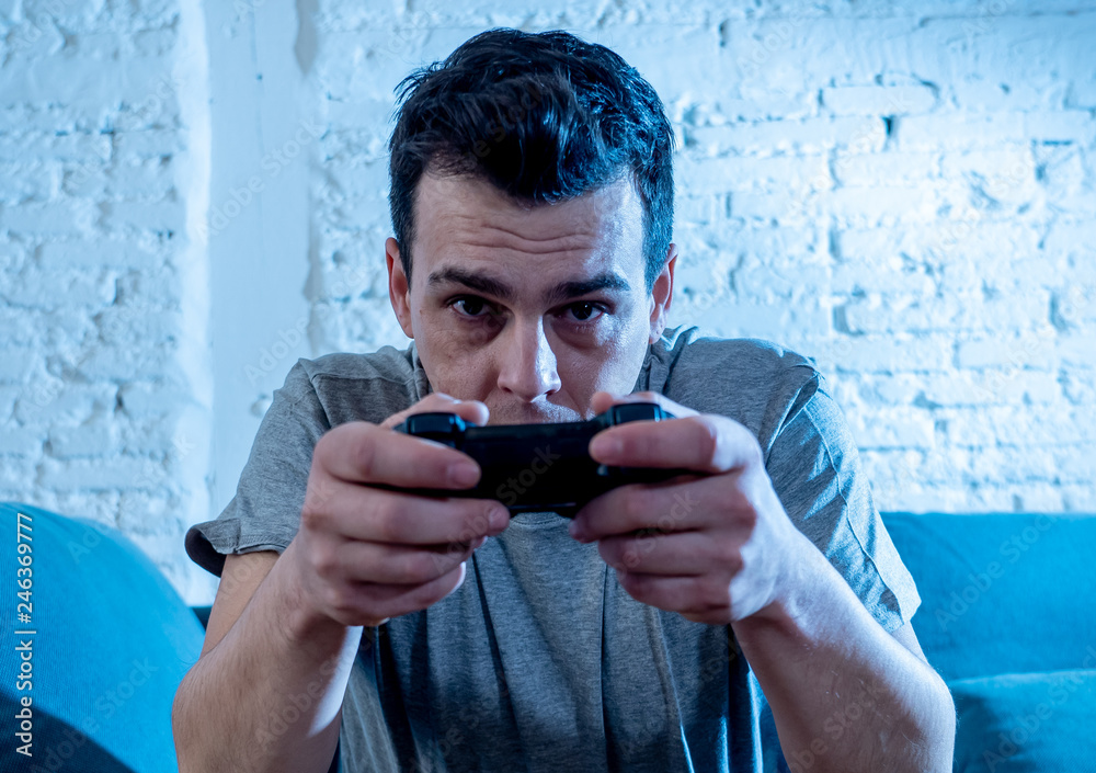 Fototapeta premium Close up portrait of young man playing video game at night addicted to it