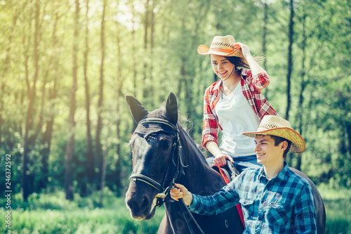 Happy nice caucasian couple riding a horse in a farm in summer day © Andreshkova Nastya
