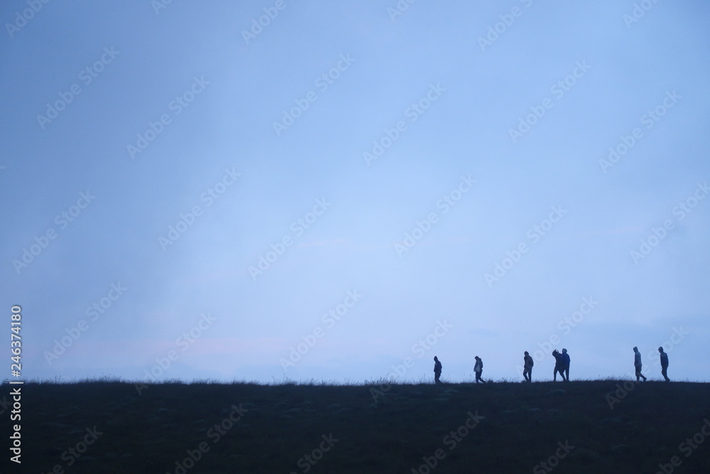 People walking on ridge in silhouette People walking on ridge in silhouette