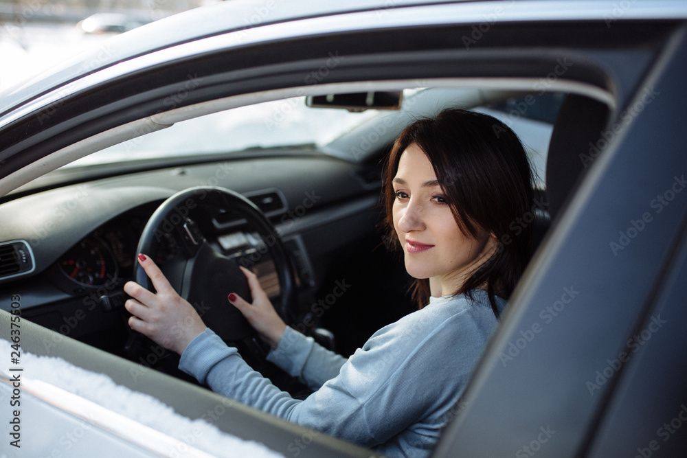 Happy woman driving a car outdoors in winter