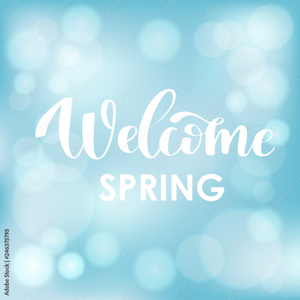 Welcome Spring. Hand drawn calligraphy and brush pen lettering on light blue sky blured background with bokeh.