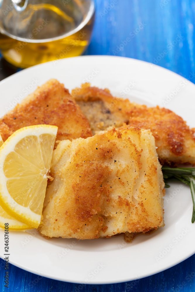 fried cod fish with lemon on white plate