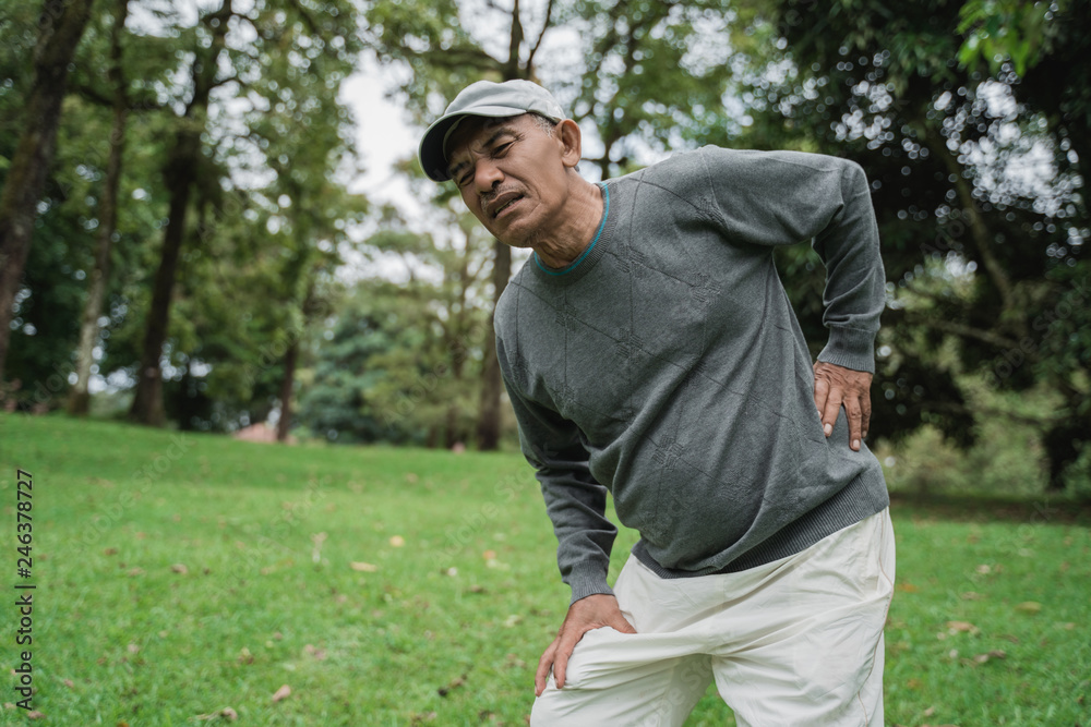 old man having back pain while in the park old man having back pain while in the park
