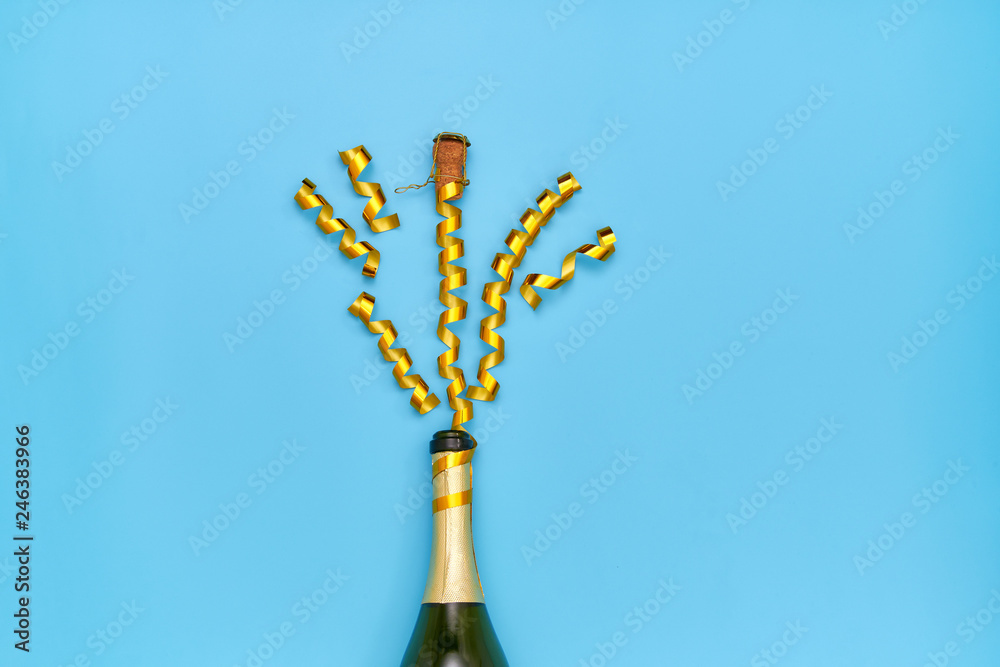 Creative photo of a champagne bottle with splashes of golden ribbons.Top view