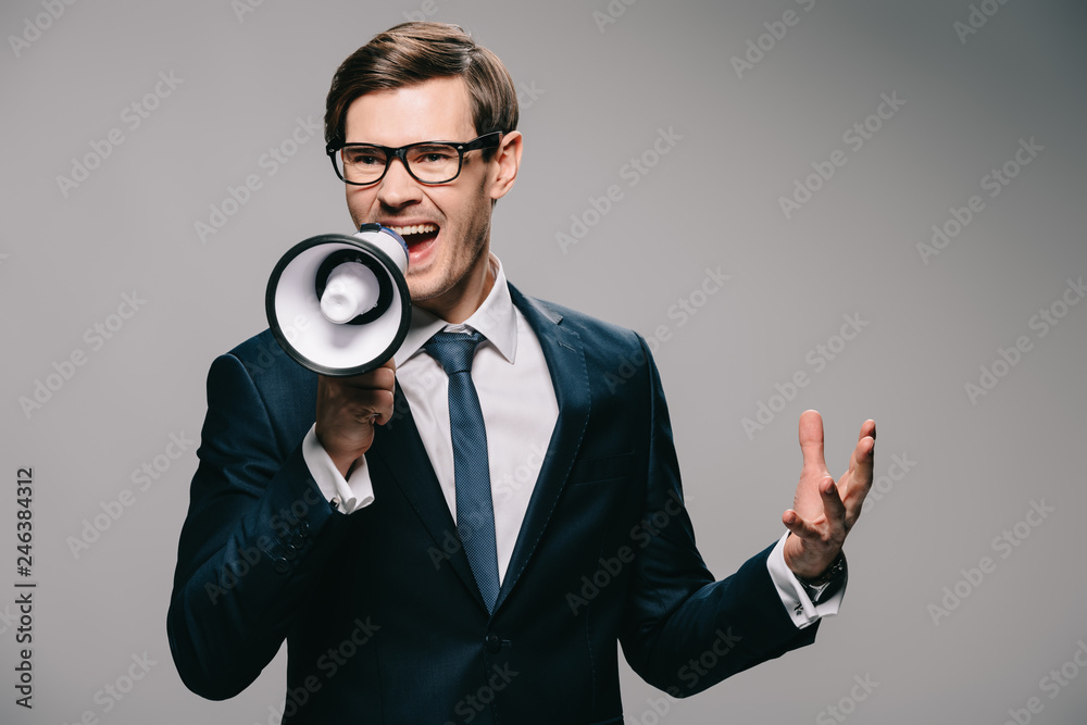 irritated businessman in suit screaming in megaphone on grey background irritated businessman in suit screaming in megaphone on grey background