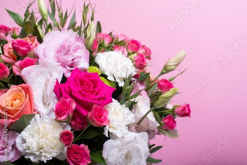 beautiful floral arrangement in the box, pink and yellow rose, pink eustoma, green and pink chrysanthemum, white carnation, pink dahlia on pink background with space for text.