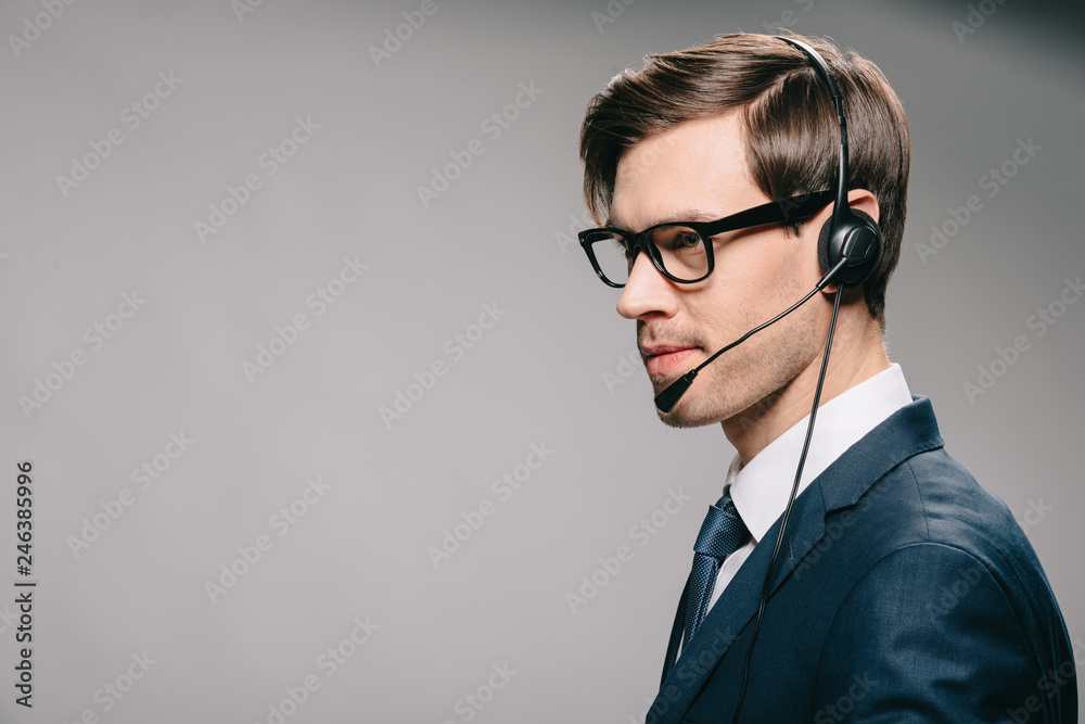 handsome man in suit and glasses wearing headset on grey background handsome man in suit and glasses wearing headset on grey background