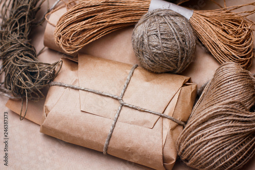 Box parcel wrapped in craft brown paper tied by hemp rope. Set of cords balls. Bundles of threads.