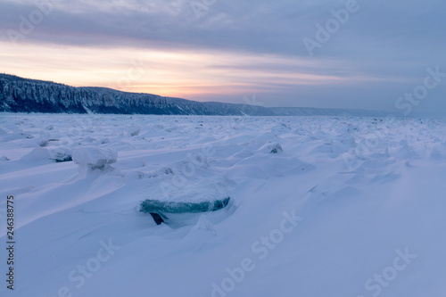 Winter landscape in pink tones with ridged ice on the frozen Lena river  at sunset in the Natural Park Lenskie Stolby (Lena Pillars), Yakutia, Russia. Pano © Tatiana Gasich