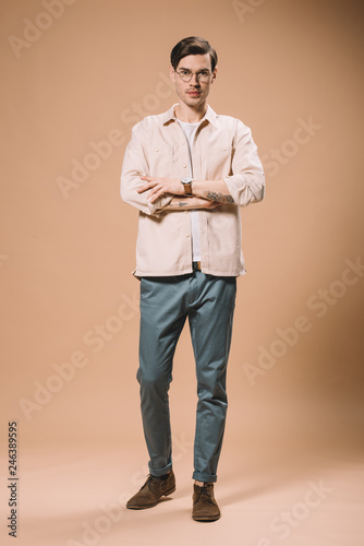 confident man standing with crossed arms  on beige background