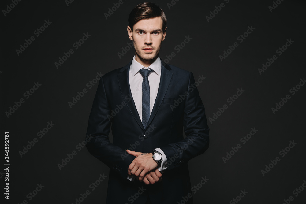 handsome and confident man standing in suit isolated on black handsome and confident man standing in suit isolated on black