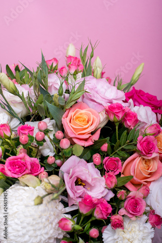 beautiful floral arrangement in the box  pink and yellow rose  pink eustoma  green and pink chrysanthemum  white carnation  pink dahlia on pink background with space for text.