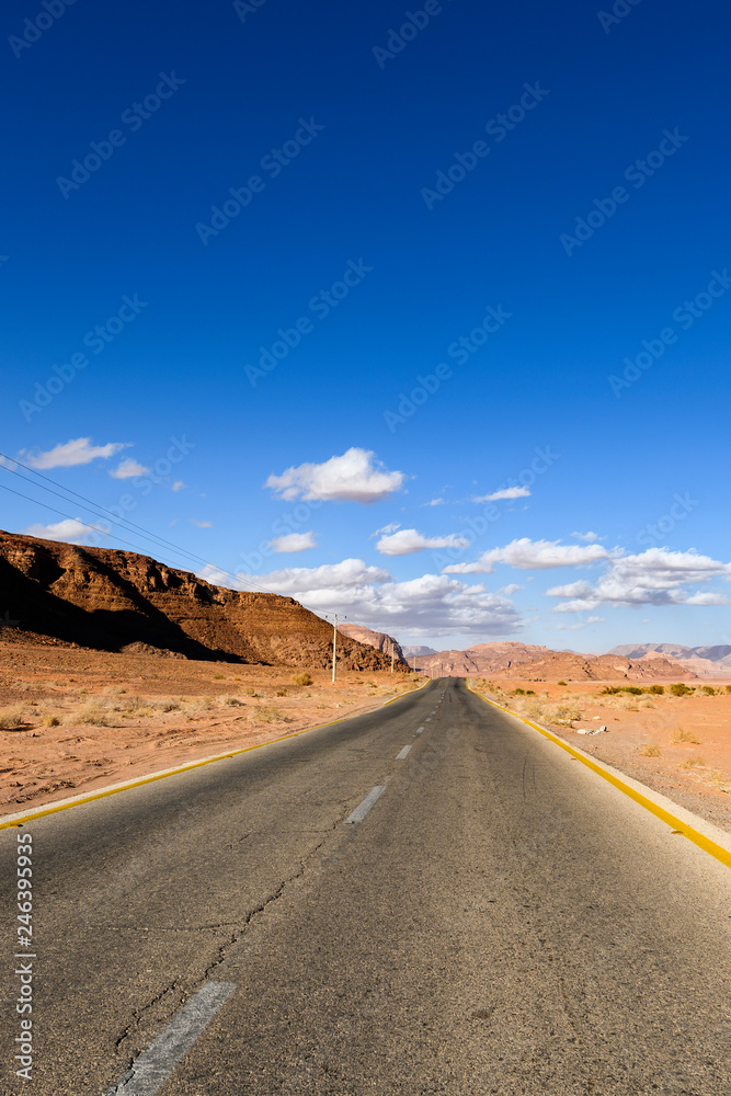 Kings highway, beautiful curvy road running through the Wadi Rum desert with rocky mountains in the distance, Jordan.