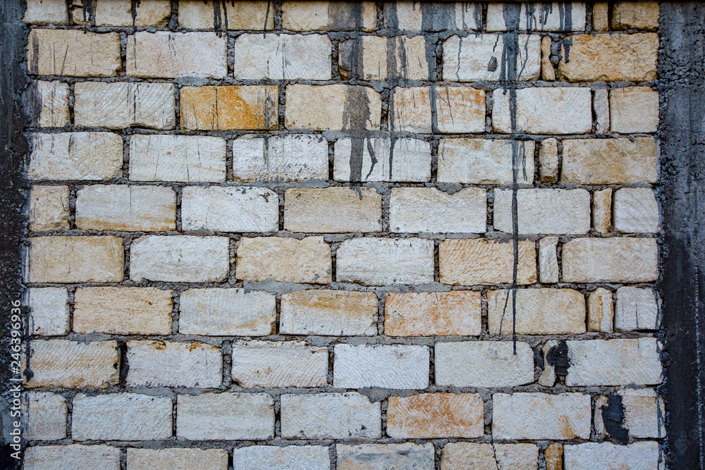 Old and weathered grungy yellow and white brick wall as seamless pattern texture background. Old and weathered grungy yellow and white brick wall as seamless pattern texture background.