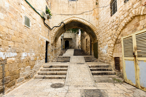 Fototapeta Naklejka Na Ścianę i Meble -  Amazing view of a small alley surrounded by the walls of the Old city of Jerusalem, Israel. The Old City is a 0.9 square kilometres walled area within the modern city of Jerusalem.