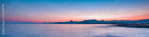 Beautiful mysterious marine landscape at sunset. Mountains, volcanic reef and ocean, panoramic banner.