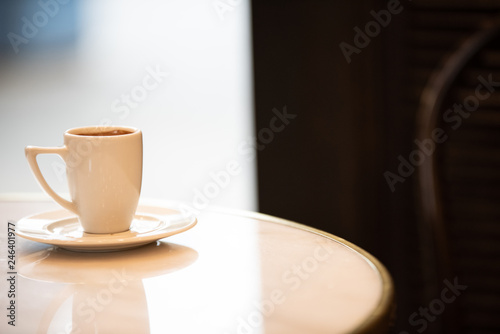 White coffee cup on a marble table inside of a cafe.